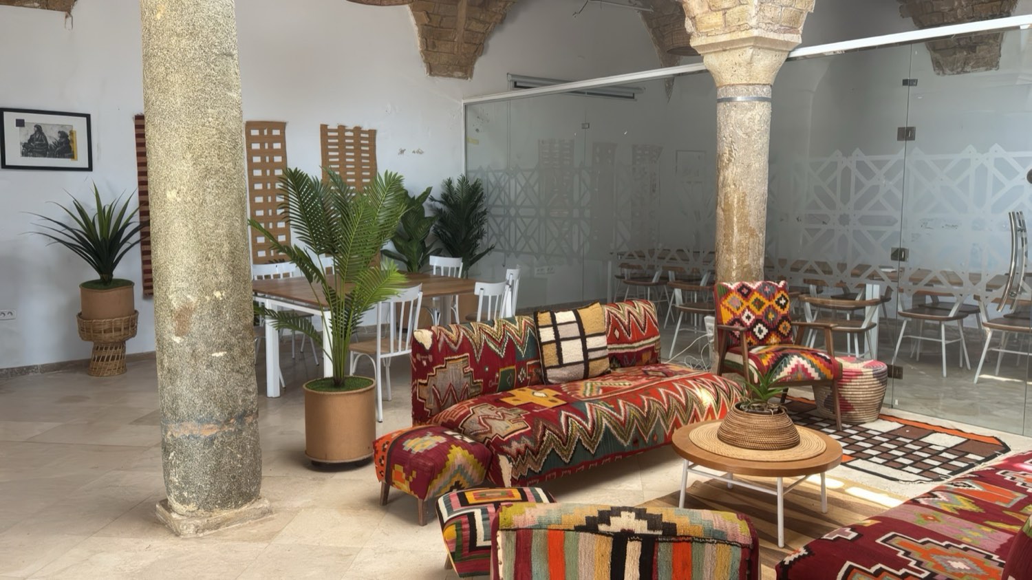 A curated creative hub in Sidi Bou Sa&iuml;d, Tunis: kilim seating, historic stone columns and a glass-walled meeting room, set up for company events